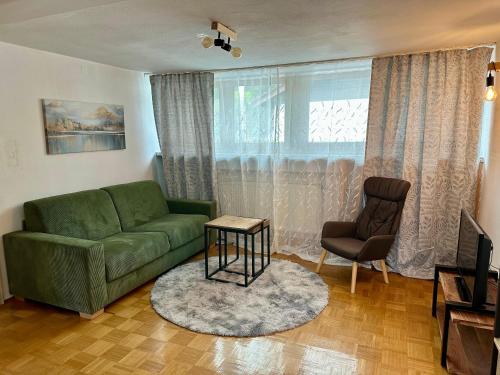 a living room with a green couch and a chair at Ferienwohnung am Staufen in Piding