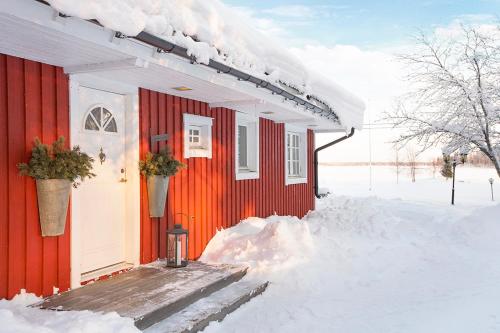 a red house with snow on the side of it at Seaside villa Swedish Lapland Luleå in Luleå