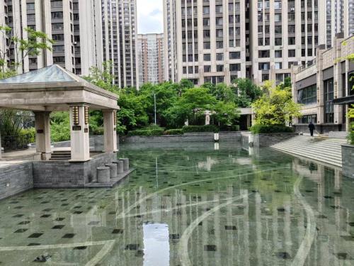 a fountain in the middle of a city with tall buildings at Central Street Apartment 1 in Harbin