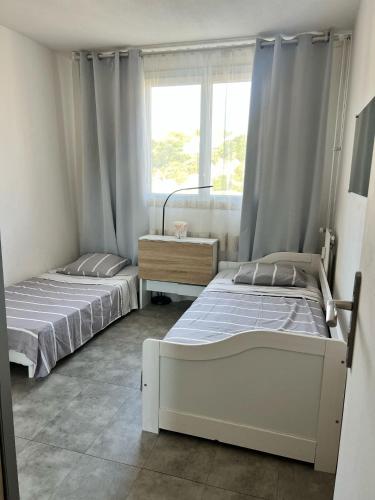 deux lits dans une chambre avec une fenêtre dans l'établissement Résidence le Lyautey, à Nice