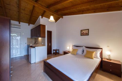 a bedroom with a large white bed and a kitchen at Kefalas Apartments in Parga