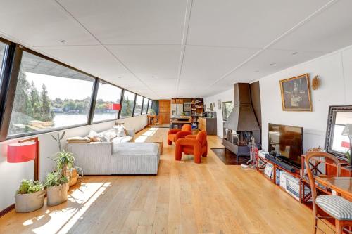 a living room with a couch and chairs and windows at Parenthèse sur l eau Elegance à Saint-Cloud in Saint-Cloud