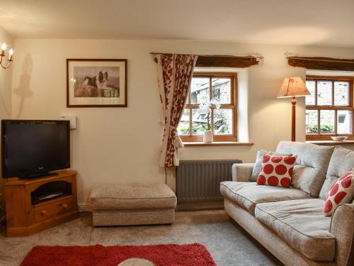 een woonkamer met een bank en een tv bij Beck Foot Cottage in Sedbergh