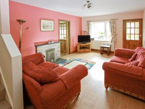 a living room with two chairs and a fireplace at Bridge Cottage in Braithwaite