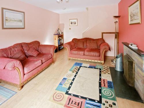 a living room with two couches and a tv at Bridge Cottage in Braithwaite