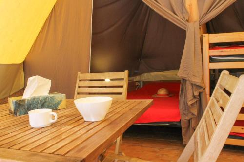 une table en bois dans une tente avec un lit dans l'établissement Camping Le Bois De Pins, à Salses-le-Chateau