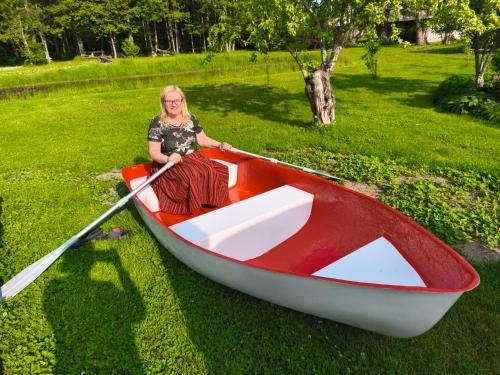 a woman sitting in a boat on the grass at Elly Kodumajutus Kihnus in Linaküla