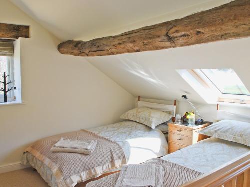 a attic bedroom with two beds and a window at Appleshine Cottage in Almondbury