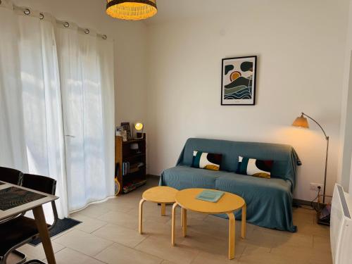 a living room with a blue couch and a table at L'escapade Landaise à 10 minutes des plages in Soustons