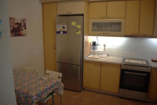 a kitchen with a stainless steel refrigerator and a table at Verde Home in Néa Meságkala