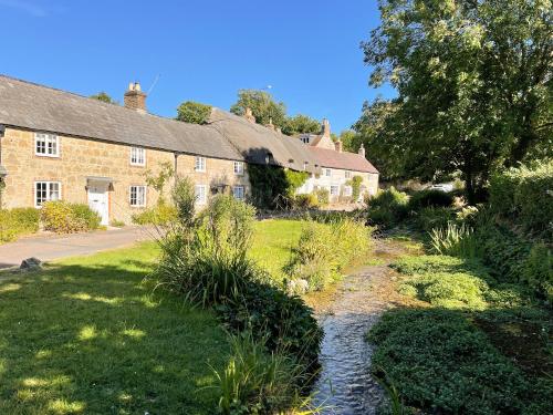 an old stone house with a stream in front of it at Winkle Cottage in Calbourne