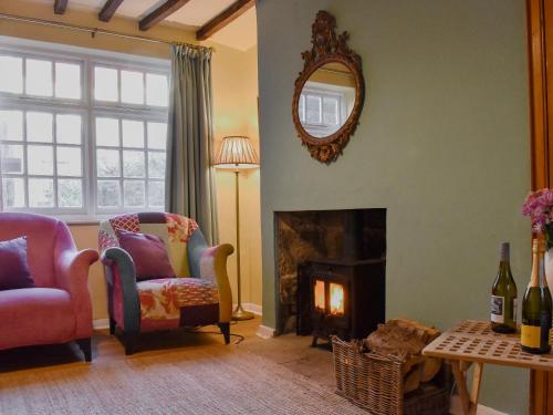 ein Wohnzimmer mit zwei Stühlen und einem Kamin in der Unterkunft Oakfield Cottage in Robin Hood's Bay