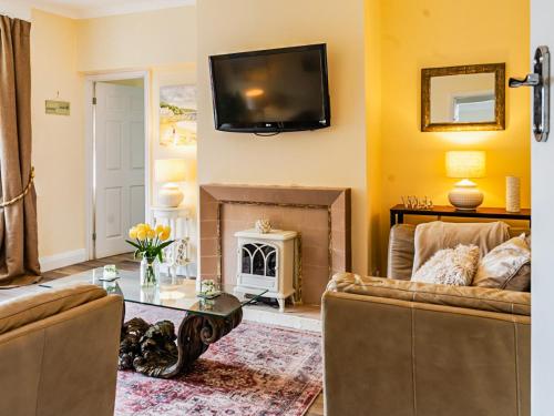 sala de estar con chimenea y TV en la pared en Beach House, en Whitley Bay