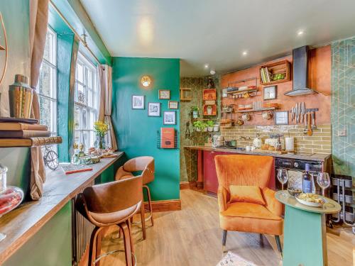 Una cocina con paredes verdes y sillas naranjas. en Buttress Retreat, en Hebden Bridge