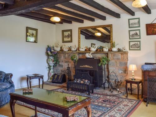 ein Wohnzimmer mit Kamin und Tisch in der Unterkunft Tudor Cottage in Bidford
