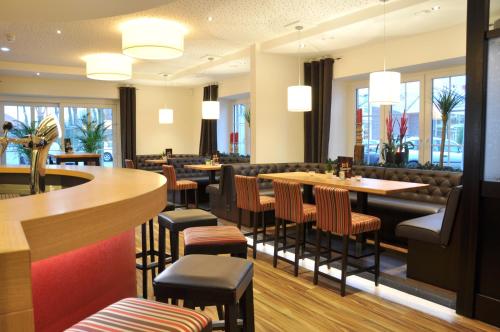 a restaurant with tables and chairs and a bar at Hotel Drei Linden in Twist