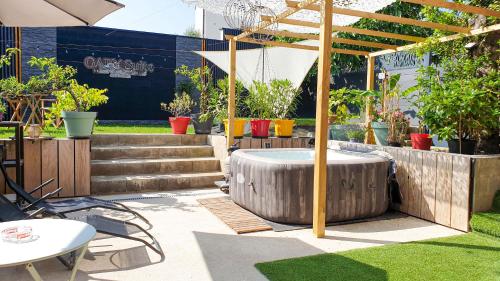 a patio with a table and an umbrella at GARY Suite - Studio Cosy, Spa et jardin privatif à 4 min de Cambrai in Awoingt