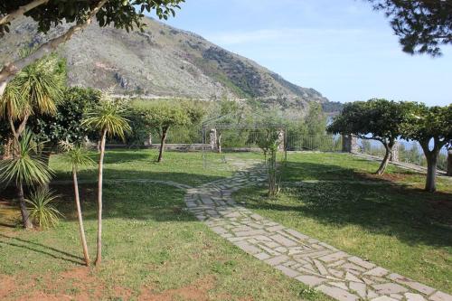 a garden with a stone path in front of a mountain at Hotel Club San Diego in Maratea