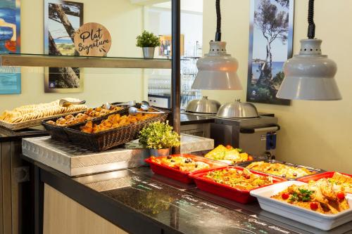 a buffet line with many different types of food at SOWELL HÔTELS Les Jardins du Cap in Cap d'Agde