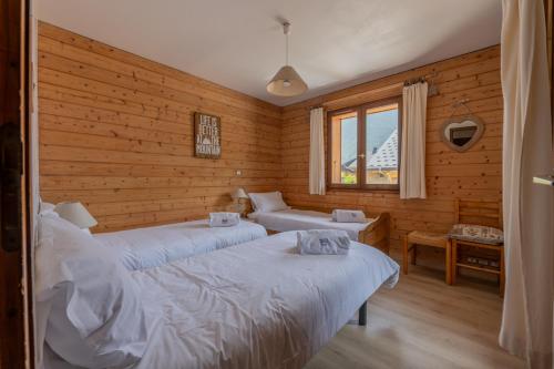 deux lits dans une chambre aux murs en bois dans l'établissement Serac 1 - Snow and Trek, à Morzine