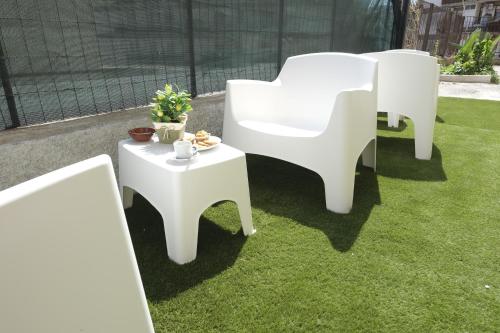 two white chairs and a table on the grass at Nonna Francesca 2 in Patti