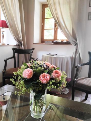 un vase de roses roses posé sur une table en verre dans l'établissement Le Relais d'Antoinette, à Prunay-sous-Ablis