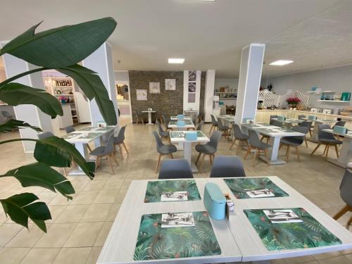 a restaurant with tables and chairs and a plant at Hotel Kinda in Castiglione della Pescaia