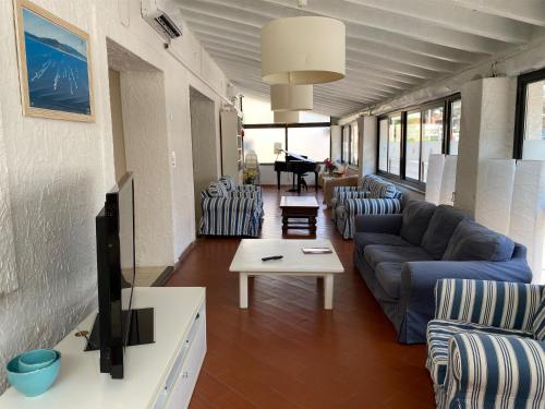 a living room with a couch and chairs and a tv at Hotel Kinda in Castiglione della Pescaia