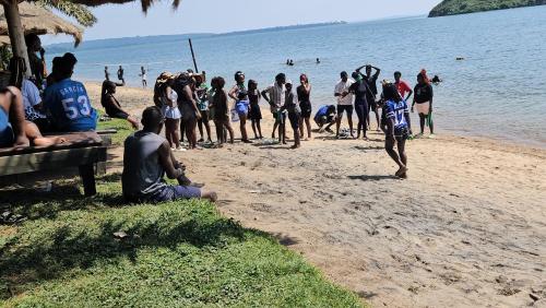 a group of people standing on a beach at Bugoma Palms Resort Sand Beach 