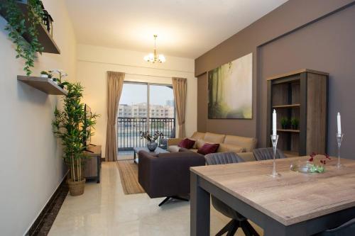 a living room with a table and a couch at BLVD - Spacious Fully Equipped Luxury Residences - Dubai - JVC in Dubai