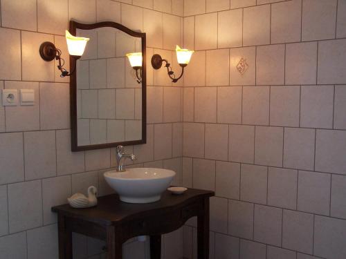La salle de bains est pourvue d'un lavabo, d'un miroir et de lumières. dans l'établissement Gîte au calme, à Nanton