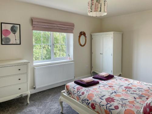 a bedroom with a bed and a dresser and a window at Bay Tree House in Dove Holes