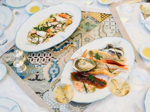 two plates of seafood on a table with glasses at Villa Sant'Andrea, A Belmond Hotel, Taormina Mare in Taormina