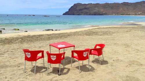 three red chairs and a table on a beach at Rosesplace Mindelo in Mindelo