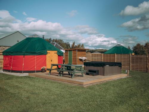 una mesa de picnic y una tienda en un patio en Moss Yurt - Uk47888, en Keilour