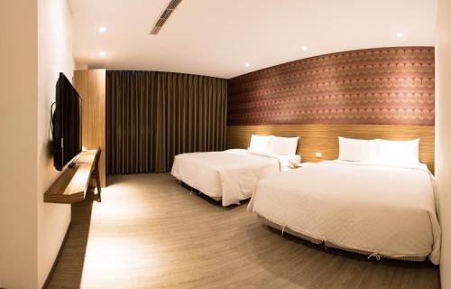 a hotel room with two beds and a television at Kousin Hotel in Kaohsiung