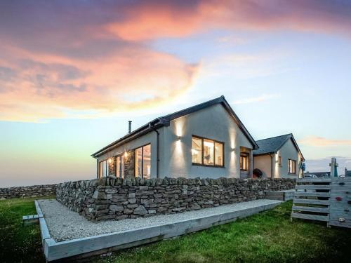 a stone house with a stone wall at Two Seas Hebrides in Eoropie
