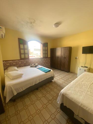 a bedroom with two beds and a window at Pousada Tamboril in Brumadinho
