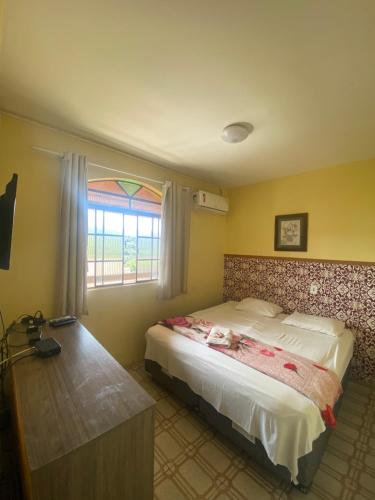 a bedroom with a large bed and a window at Pousada Tamboril in Brumadinho