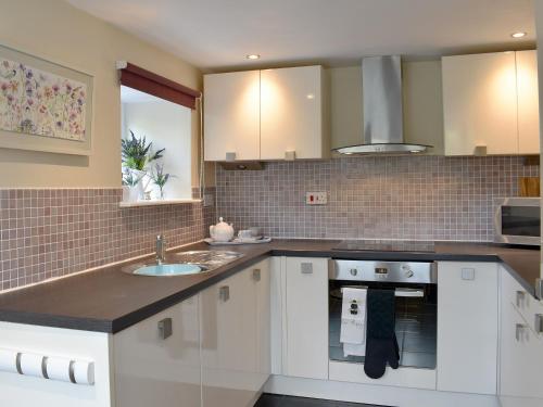 a kitchen with white cabinets and a sink at The Coach House Halifax in Halifax