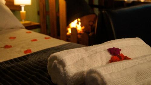 a bed with a white blanket with red flowers on it at Chalés Verde Maua in Visconde De Maua