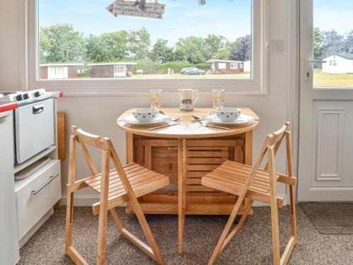 a kitchen with a table and chairs and a window at Driftwood in Mundesley