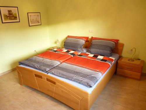 ein großes Bett in einem Schlafzimmer mit orangefarbener und grauer Bettwäsche in der Unterkunft Ferienwohnung Hutterer in Bad Griesbach