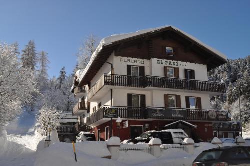 a large building in the snow with cars parked in front at Hotel El Paso in Fai della Paganella