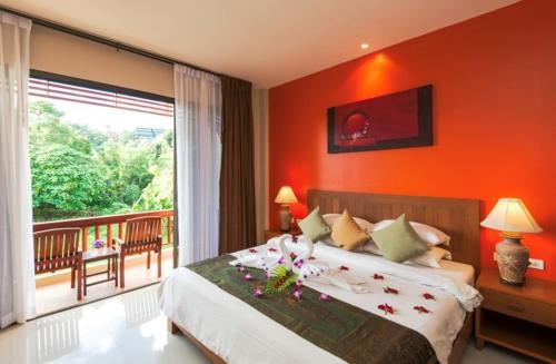 a bedroom with a bed with orange walls and a balcony at Katanoi Resort in Kata Beach