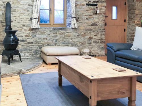 a living room with a wooden coffee table and a stove at The Old Cow Shed in Barlow