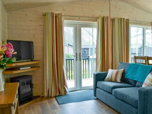 a living room with a blue couch and a television at Bransty in Keswick