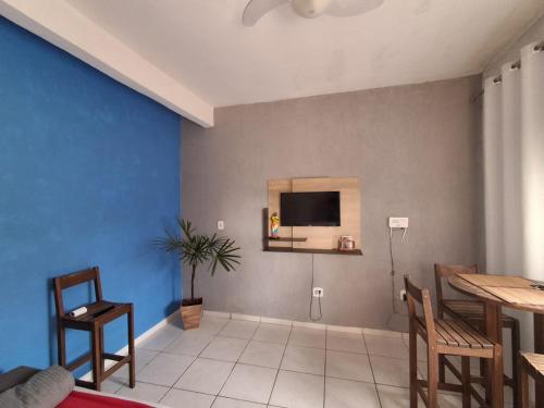 a living room with a tv on a blue wall at Casa AMORA 2 quartos PISCINA in Aparecida