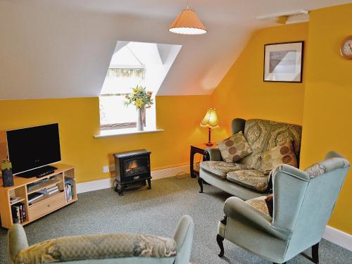 a living room with a couch and a tv at Westonbirt Cottage in Shipton Moyne