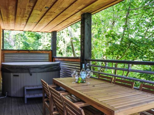 a wooden table and chairs on a deck with a hot tub at Gwynant Lodge - Uk47608 in Caernarfon